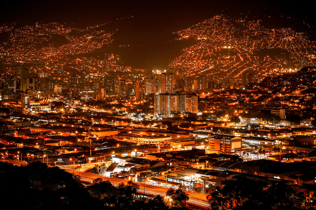 Medellín’s buildings and hillside neighborhoods illuminated at night.
